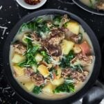 Sausage, potato and kale soup (Zuppa Toscana) in dark bowls on a dark surface.
