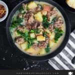 Sausage, potato and kale soup (Zuppa Toscana) in dark bowls on a dark surface.