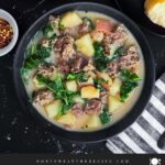 Sausage, potato and kale soup (Zuppa Toscana) in dark bowls on a dark surface.