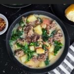 Sausage, potato and kale soup (Zuppa Toscana) in dark bowls on a dark surface.