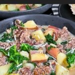 Sausage, potato and kale soup (Zuppa Toscana) in dark bowls on a dark surface.