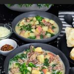 Sausage, potato and kale soup (Zuppa Toscana) in dark bowls on a dark surface.