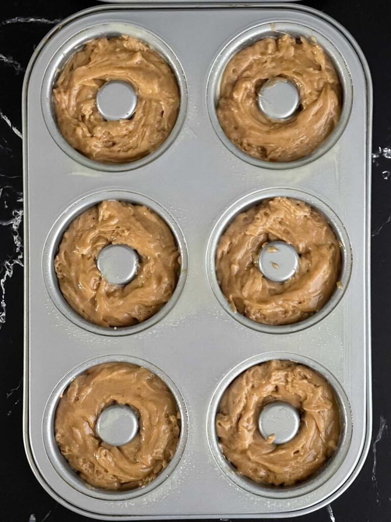 Baked apple cider donut batter divided into a six section donut pan.