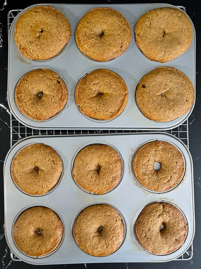 Baked apple cider donuts in a donut pan on a wire rack.