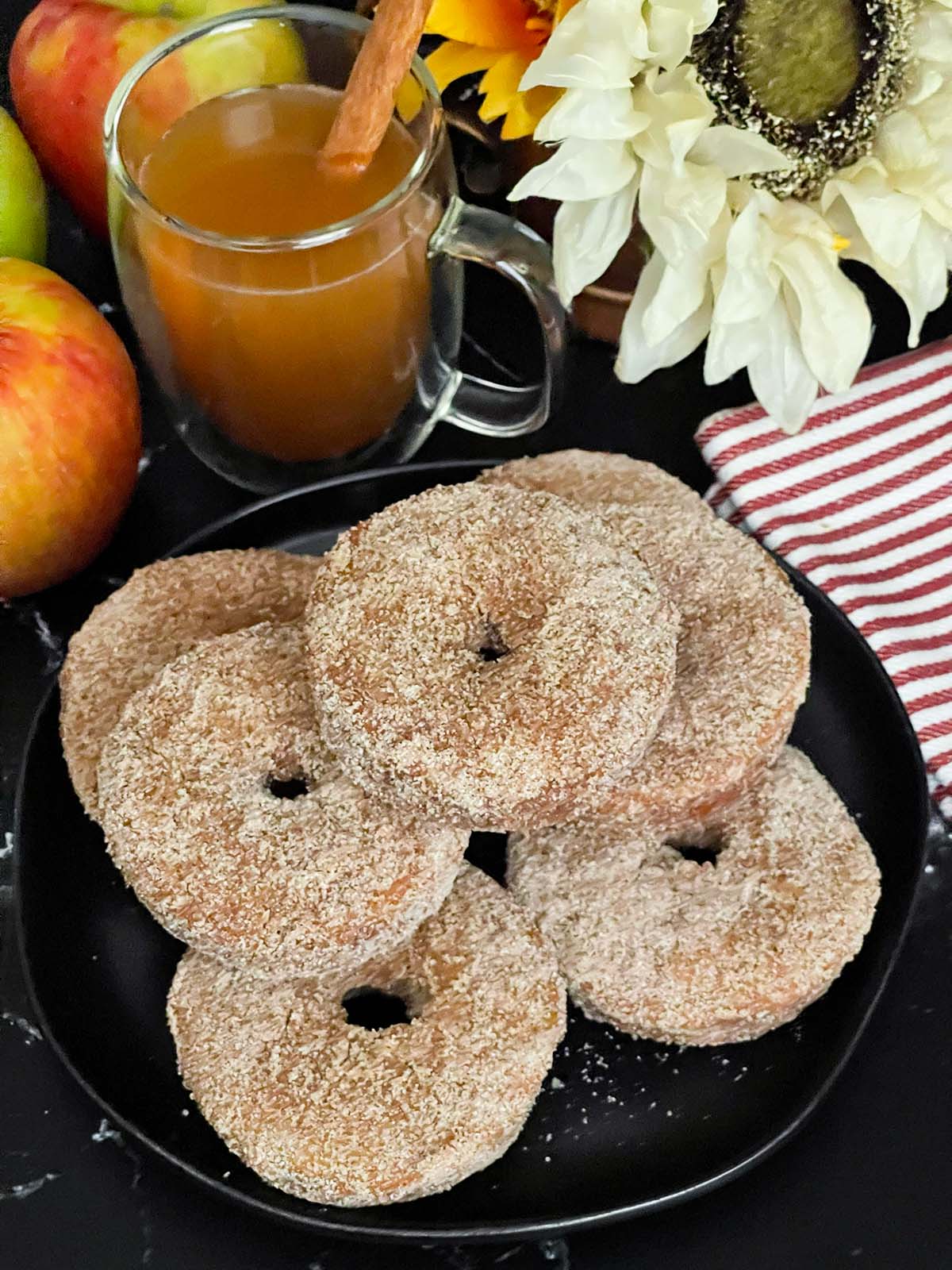 Baked apple cider donuts stacked on a dark plate.