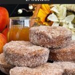 Baked apple cider donuts stacked on a dark plate on a dark surface.