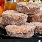 Baked apple cider donuts stacked on a dark plate on a dark surface.