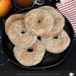 Baked apple cider donuts stacked on a dark plate on a dark surface.