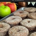 Baked apple cider donuts on a wire rack over a parchment paper lined baking pan.