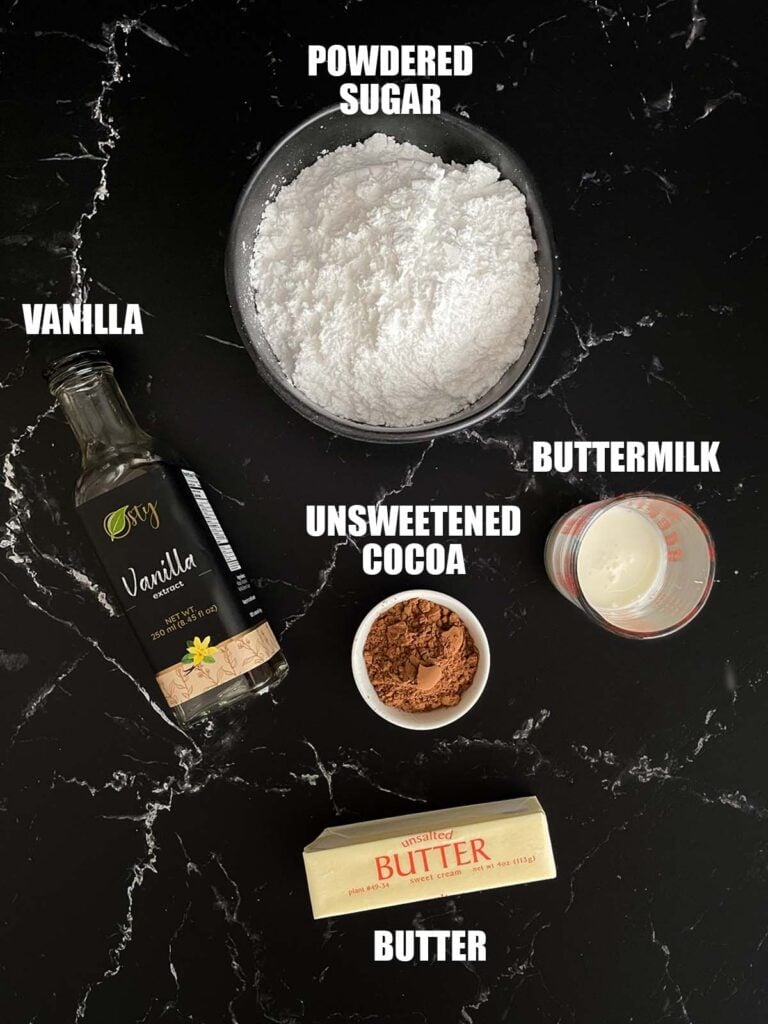 Chocolate buttermilk icing recipe ingredients on a dark surface.