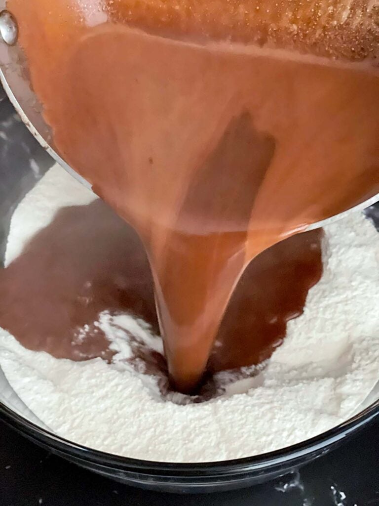 Boiled chocolate mixture being poured into the dry ingredients for buttermilk brownies.