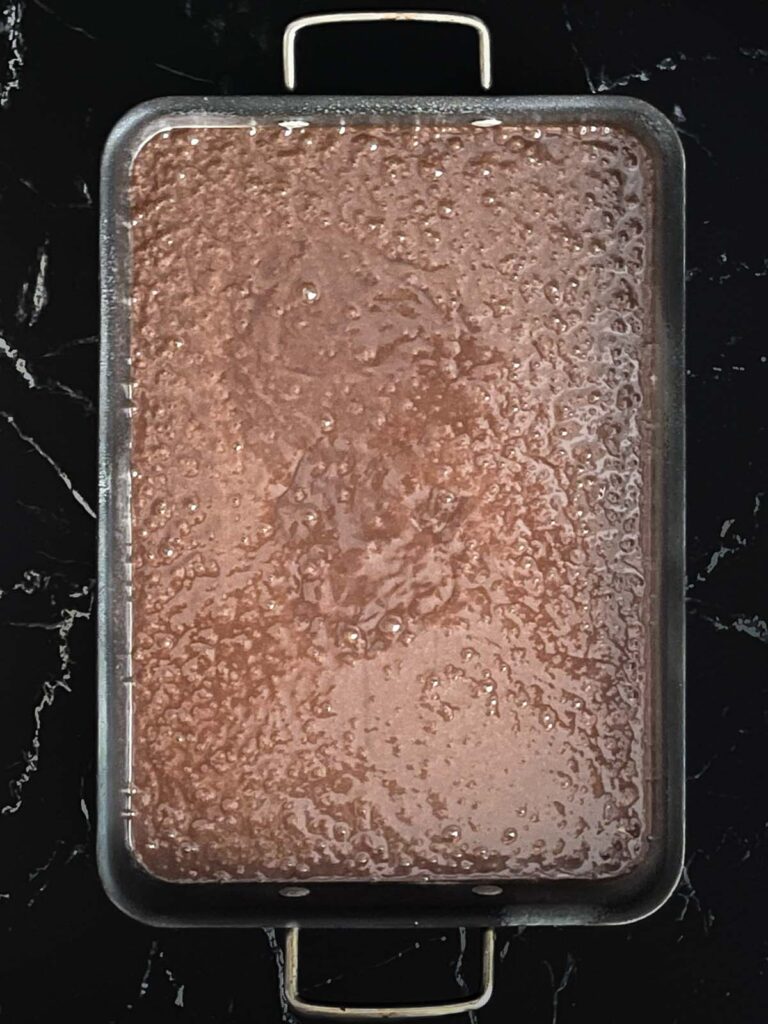 Buttermilk brownie batter poured into the prepared baking pan on a dark surface.