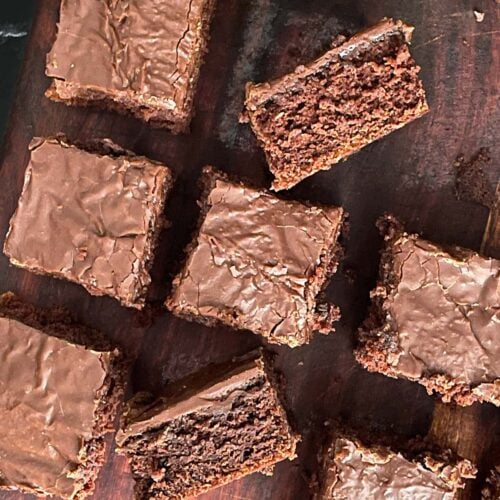 Sliced buttermilk brownies on a wooden cutting board.