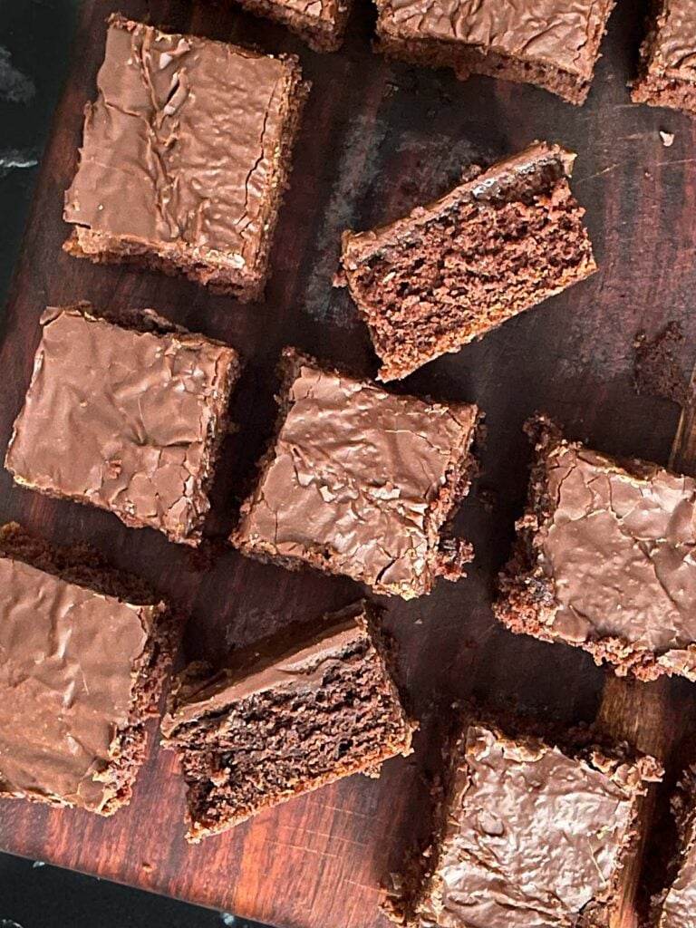 Sliced buttermilk brownies on a wooden cutting board.