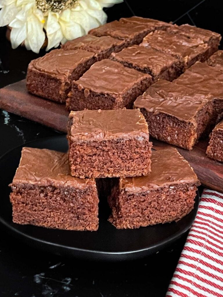 Three buttermilk brownies stacked on a dark plate.