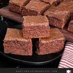 Three buttermilk brownies on a dark plate on a dark surface.