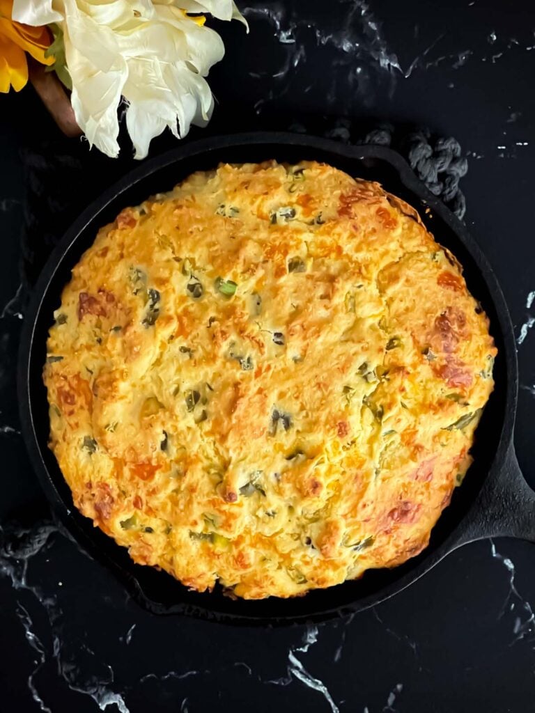 Cheddar jalapeno cornbread, cooked, in a cast iron skillet.