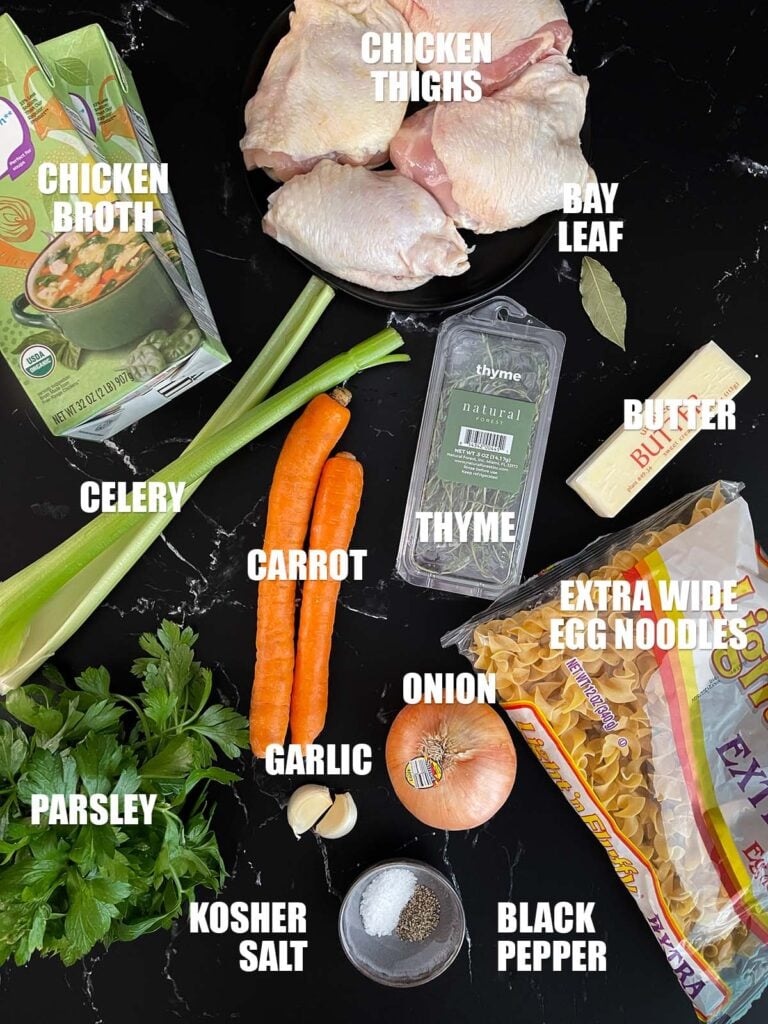 Chicken noodle soup recipe ingredients on a dark surface.