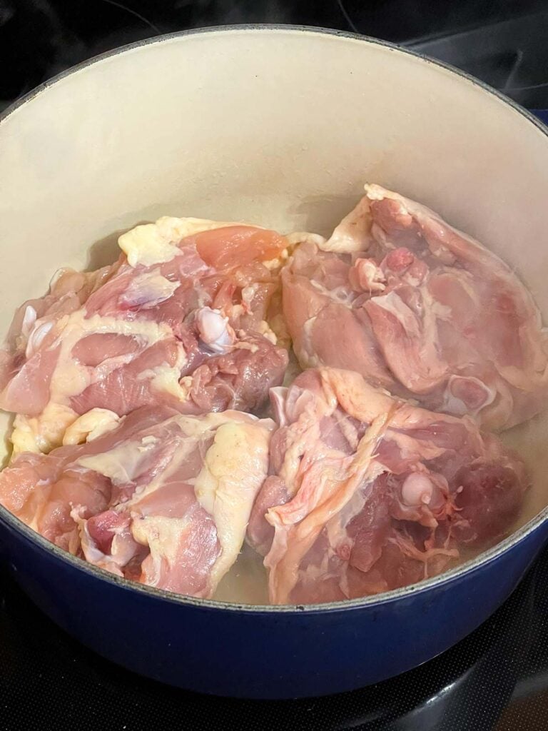 Chicken thighs browning in a large dutch oven.