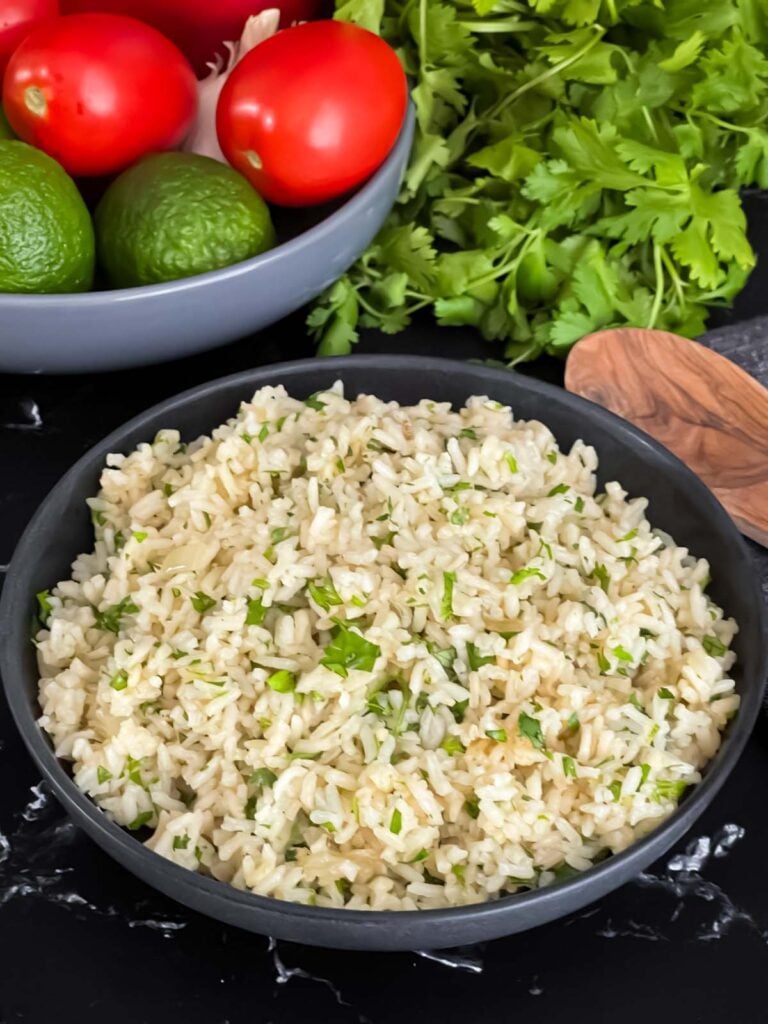 Cilantro lime rice in a dark bowl on a dark surface.