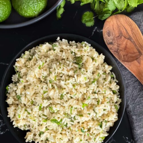Cilantro lime rice in a dark bowl on a dark surface.