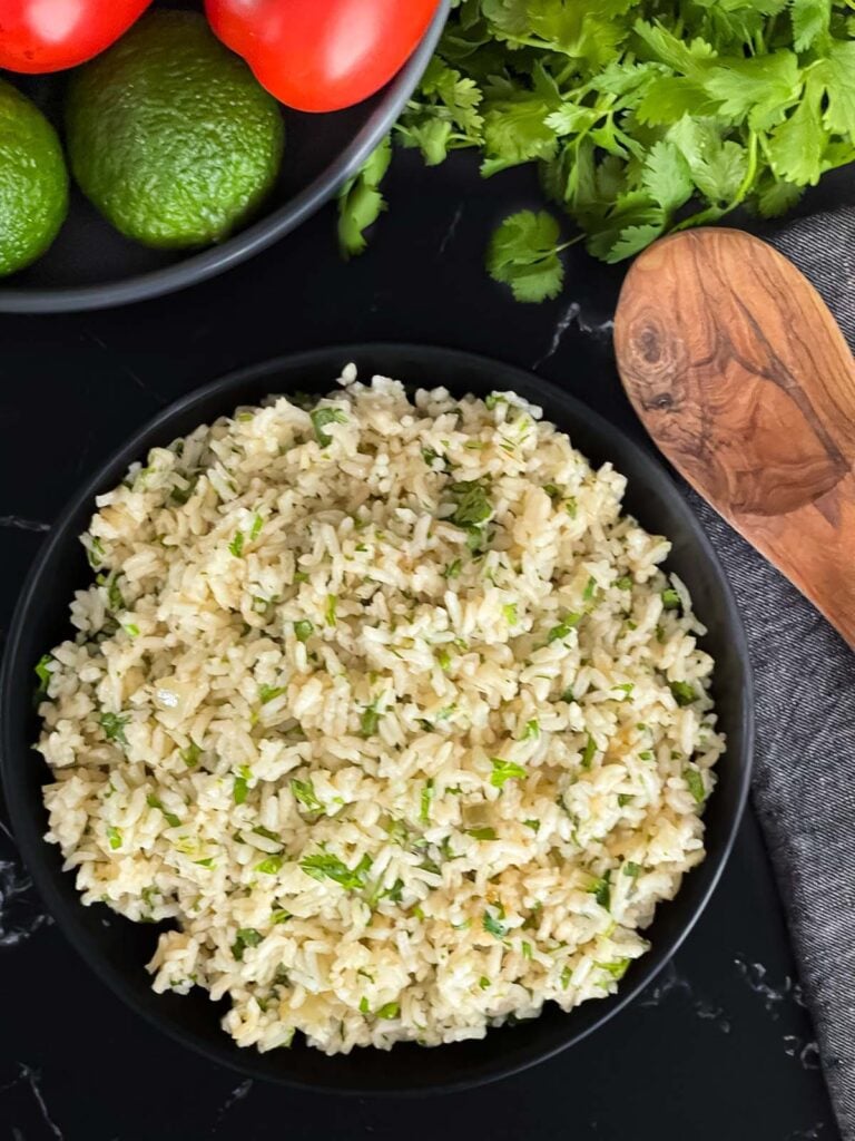 Cilantro lime rice in a dark bowl on a dark surface.