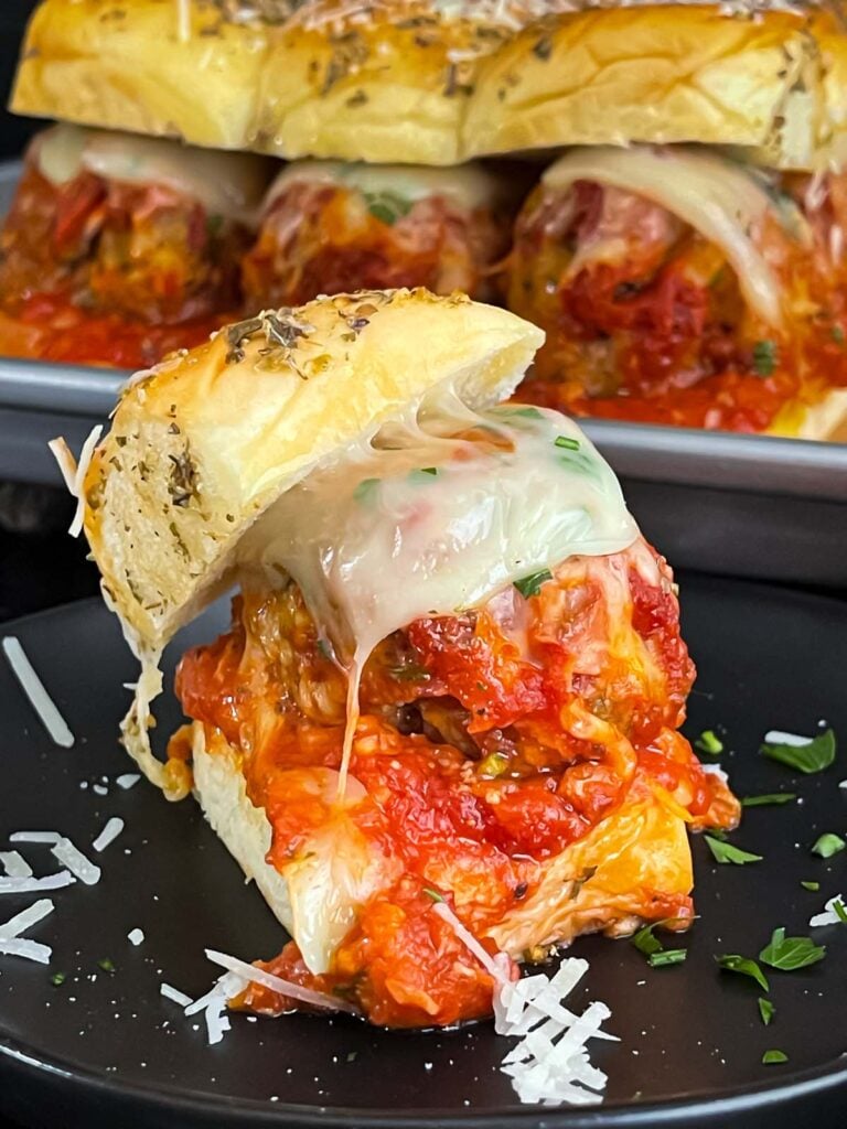 A meatball slider on a dark plate.