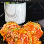 Easy baked parmesan meatballs garnished with chopped Italian flat leaf parsley on a dark plate.