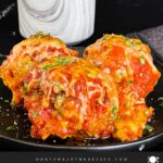 Easy baked parmesan meatballs garnished with chopped Italian flat leaf parsley on a dark plate.