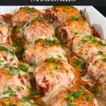 Easy baked parmesan meatballs garnished with chopped Italian flat leaf parsley in a light casserole dish.