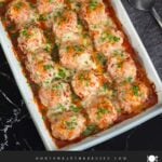 Easy baked parmesan meatballs garnished with chopped Italian flat leaf parsley in a light casserole dish.