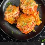 Easy baked parmesan meatballs garnished with chopped Italian flat leaf parsley on a dark plate.