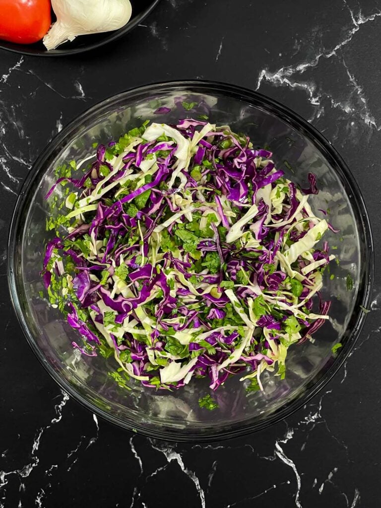 Cilantro lime slaw fully mixed in a glass bowl.