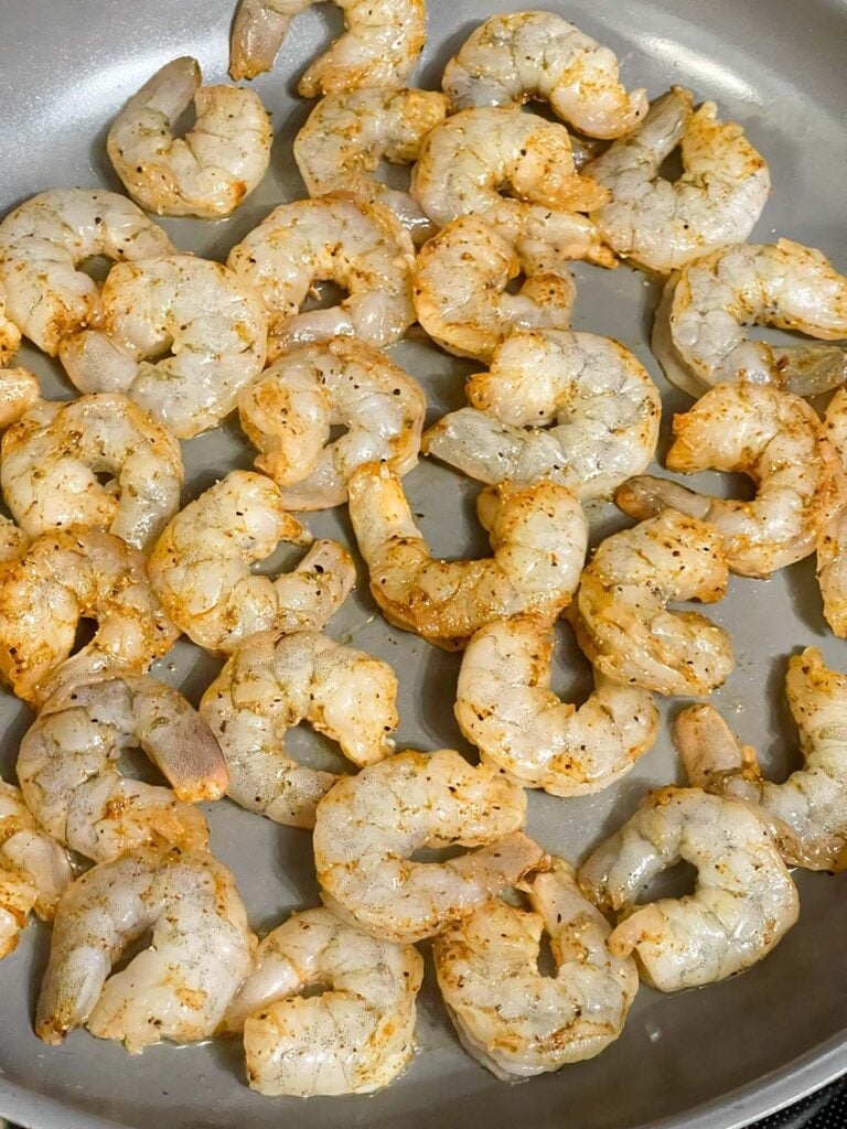 Raw shrimp arranged in a skillet before cooking.