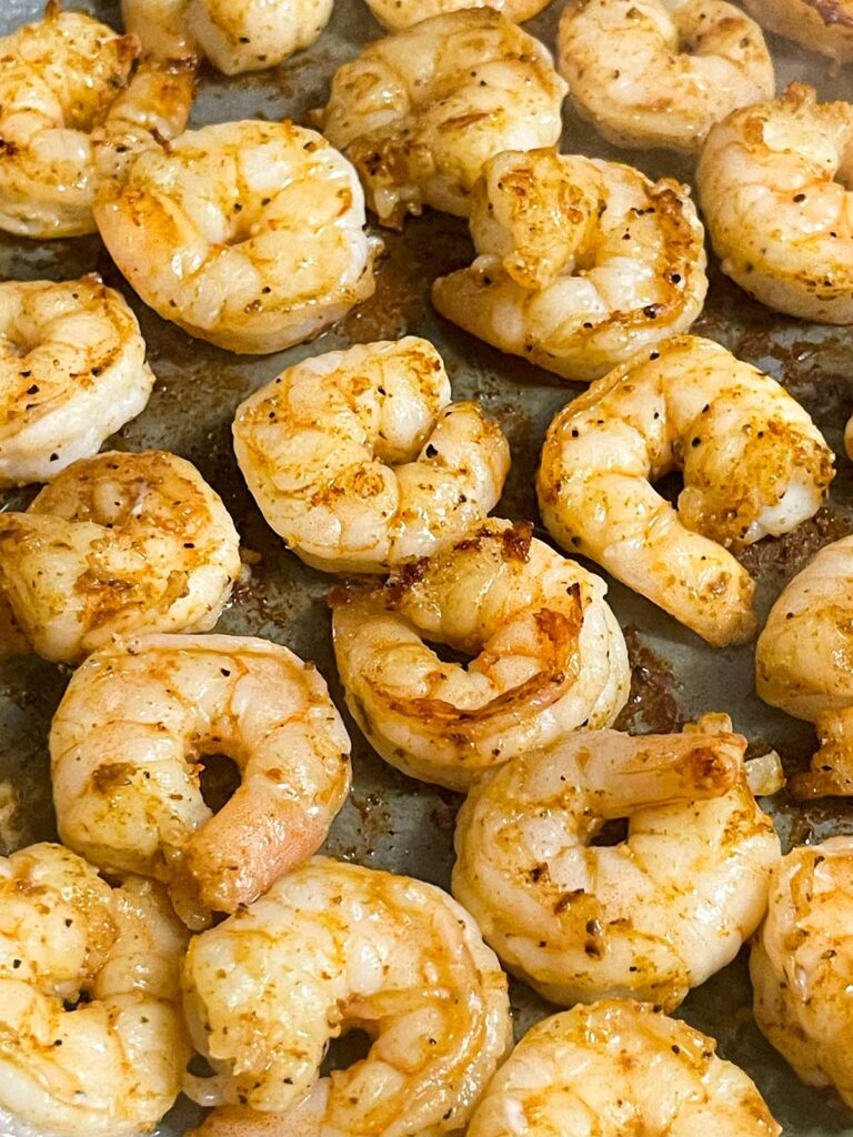 Shrimp cooking in a skillet, turning pink and opaque.