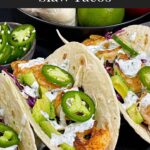 Shrimp tacos served with slaw, jalapeños, and fresh vegetables arranged for a taco-night spread.