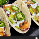 Shrimp tacos served with slaw, jalapeños, and fresh vegetables arranged for a taco-night spread.