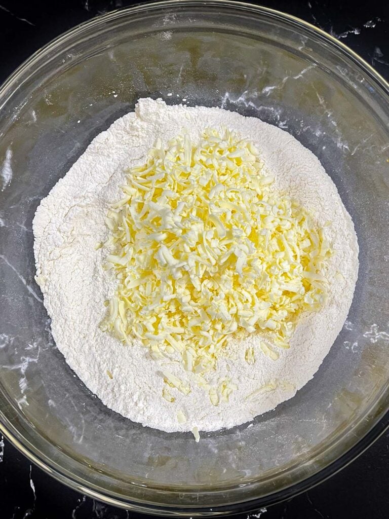 Shredded frozen butter added to the dry ingredients for cranberry orange scones.