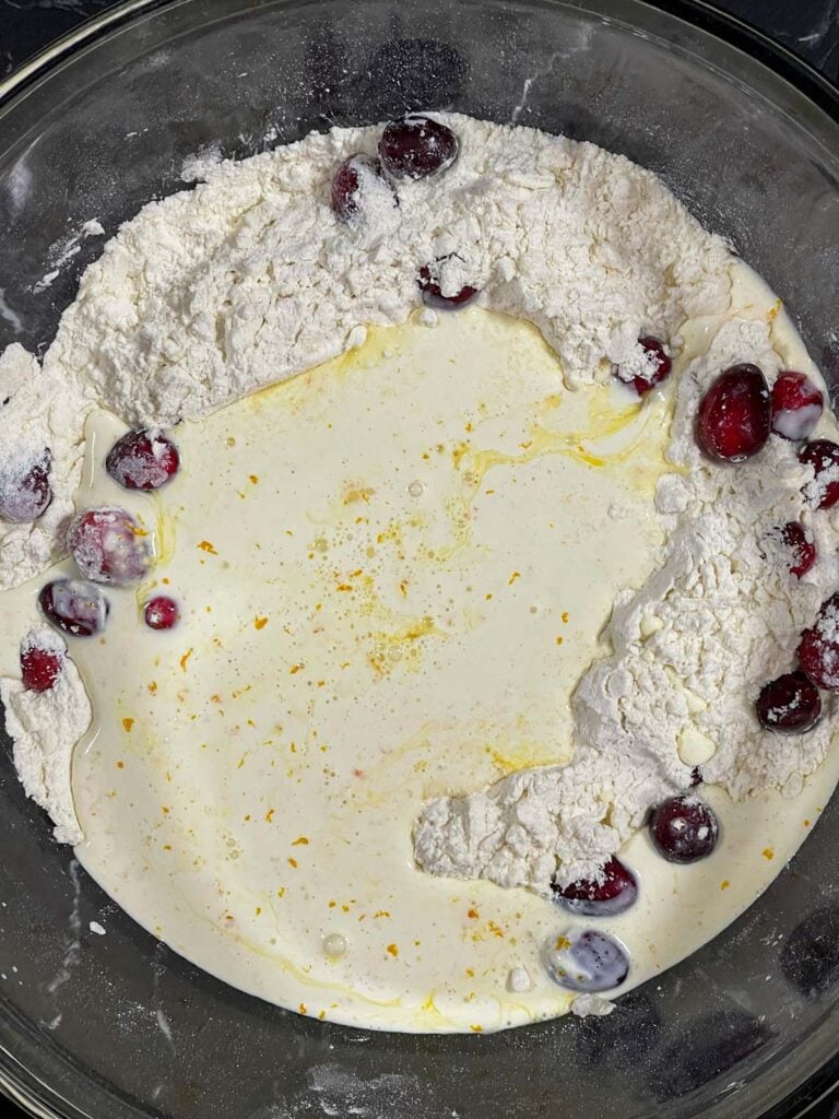 Wet ingredients poured into the well of the dry ingredients for cranberry orange scones.