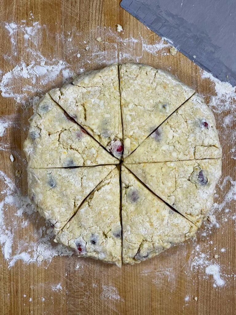 Cranberry orange scone dough circle sliced into 8 pieces.