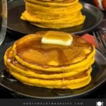 Stack of fluffy pumpkin pancakes with butter and maple syrup, golden edges on a dark plate.