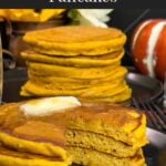 Stack of fluffy pumpkin pancakes with butter and maple syrup, golden edges on a dark plate.