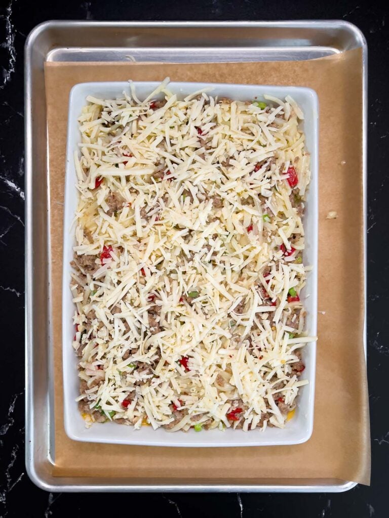 Unbaked sausage hashbrown breakfast casserole spread evenly in a 9x13 baking dish.