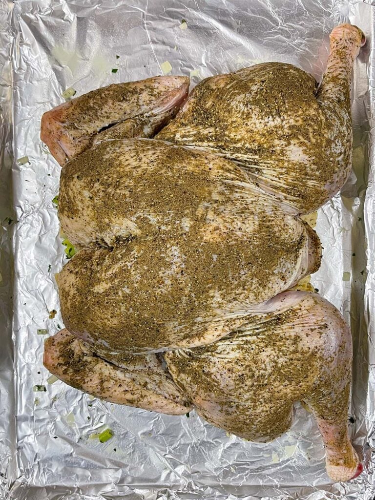 Spatchcocked turkey positioned directly on top of the stuffing on a baking sheet.