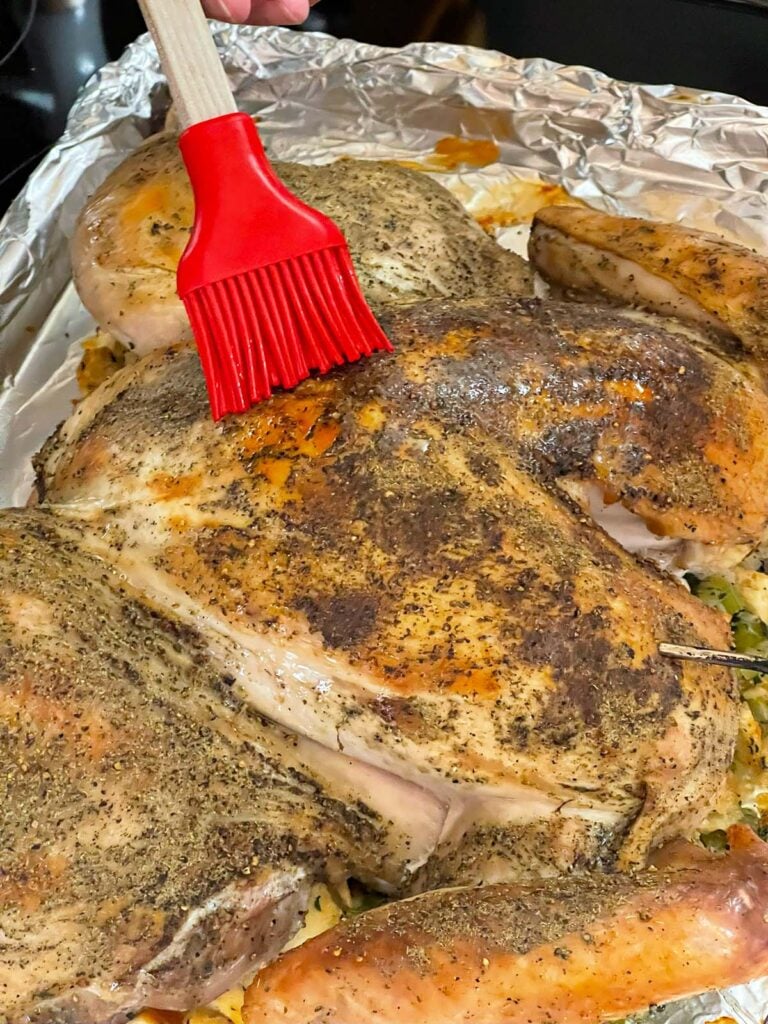 Spatchcocked turkey being basted with melted butter during roasting.