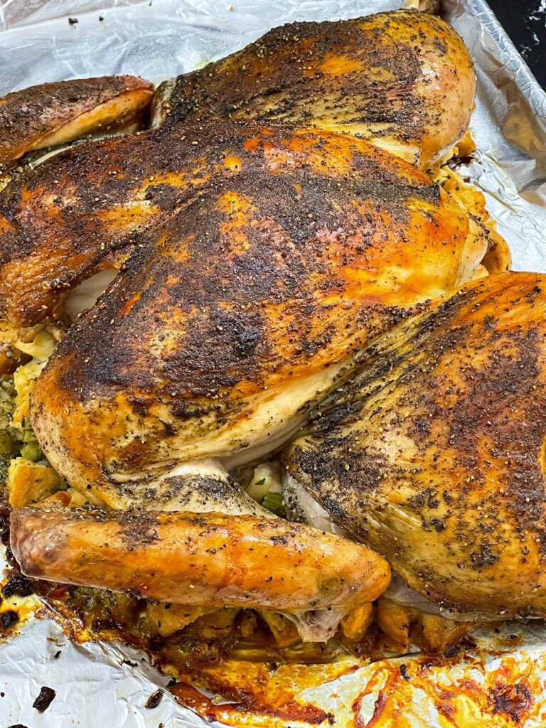 Oven-roasted spatchcock turkey resting on the cooked stuffing.