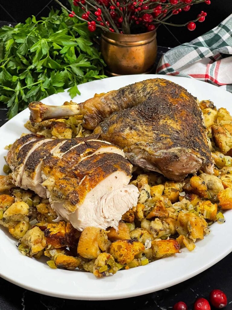 Cut turkey on a bed of stuffing on a white platter.