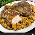 Cut turkey on a bed of stuffing on a white platter.