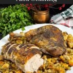 Cut turkey on a bed of stuffing on a white platter.