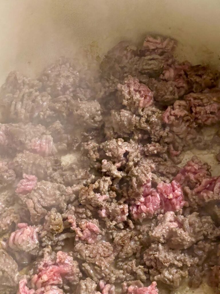 Ground beef cooking in a dutch oven.